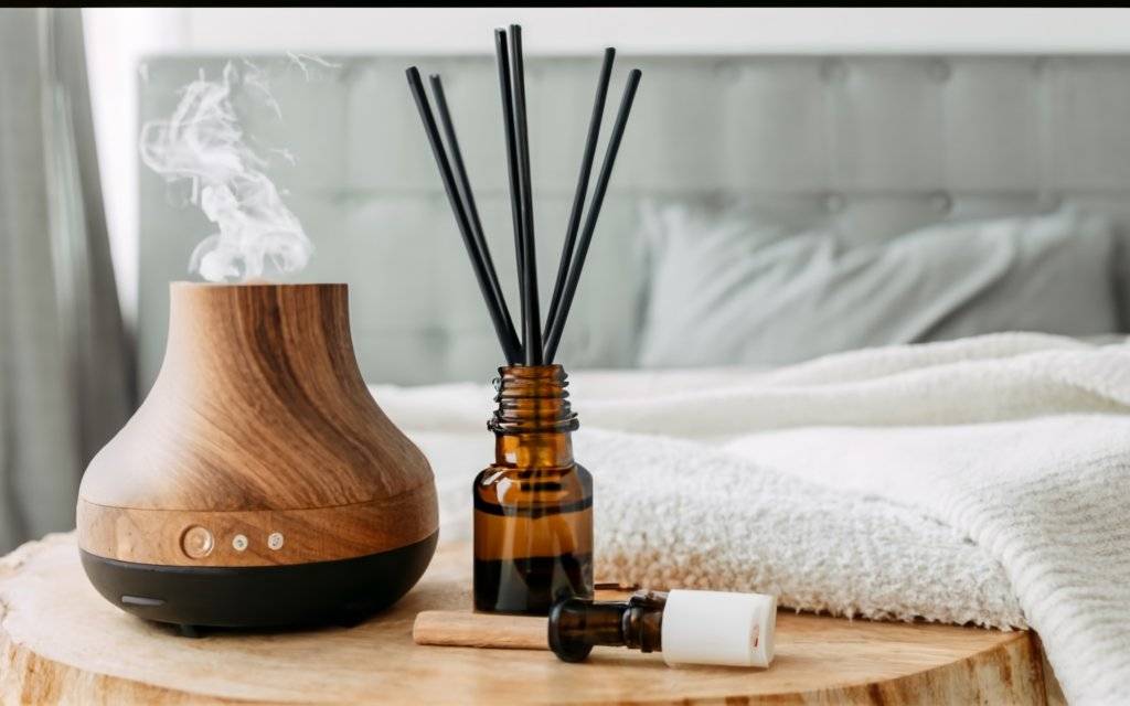 Aromatherapy oils and a diffuser next to a bed
