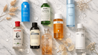 9 skincare toner bottles arranged on a white marble surface with dried botanicals,