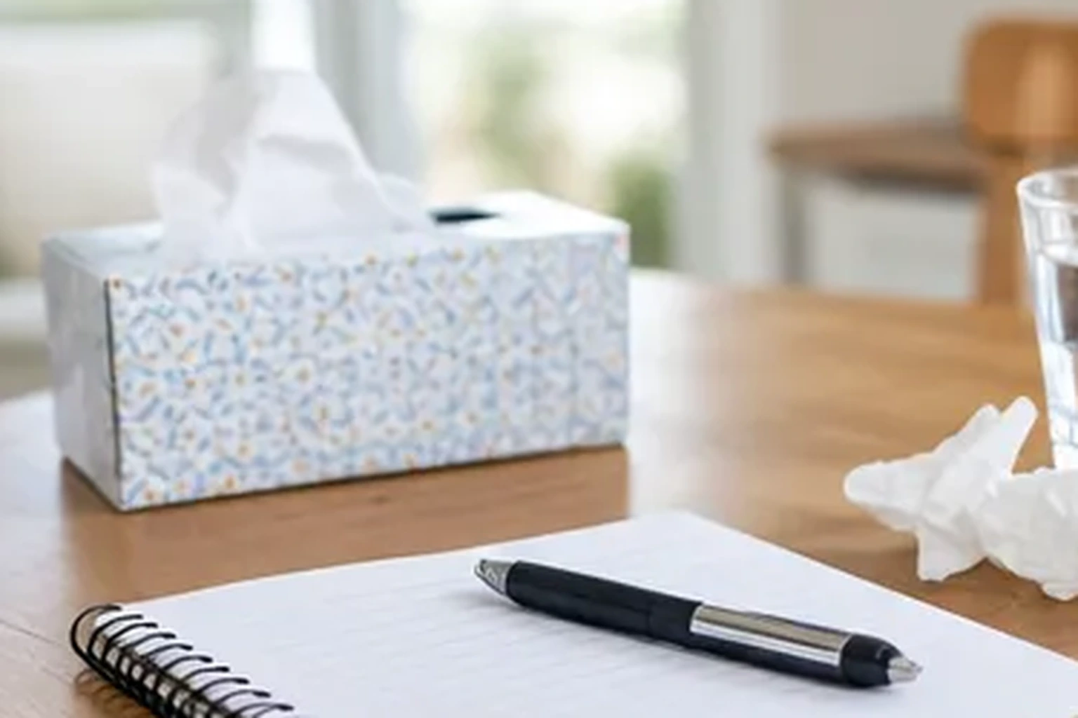 Blank notebook with tissues and a glass of water on a table