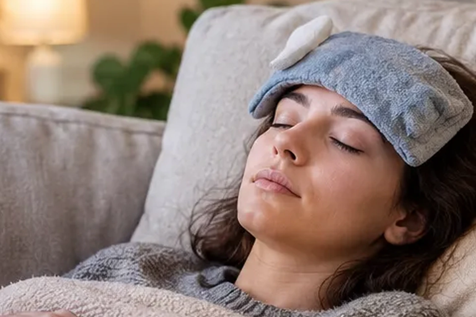 Woman resting on a couch with a compress on her forehead